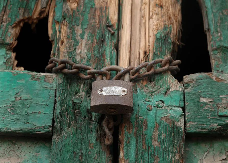 Close-up of a vintage green door with a rusty padlock and chain in Egypt.
